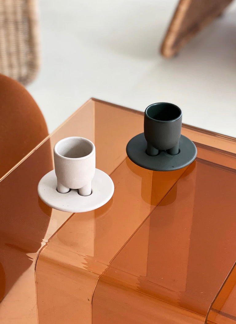 off white espresso cup and dark green espresso cup on orange plexiglass table